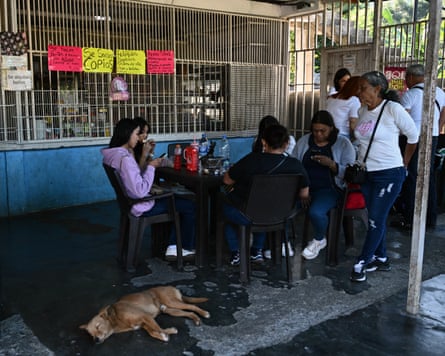 Relatives of prisoners expecting the release of their loved ones wait outside El Rodeo prison in Caracas on January 9, 2026. A dog lies on the floor next to them.