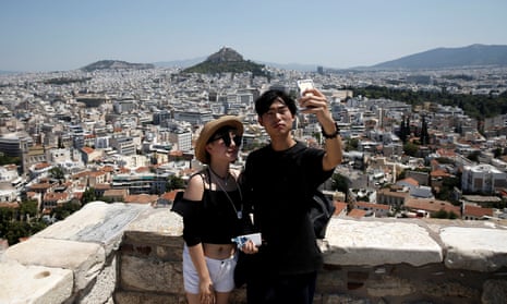 Tourists take a selfie as they visit the Acropolis hill in Athens