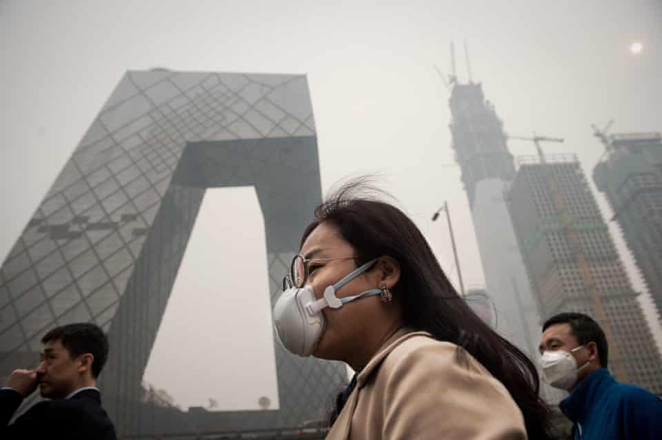 A woman wearing a protective pollution mask walks on a street in Beijing in 2017
