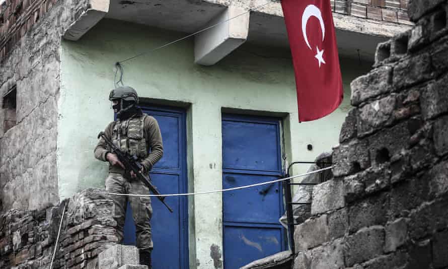 A soldier stands guard at a neighborhood as Turkish Security Forces carry out a counter - terrorism operation.