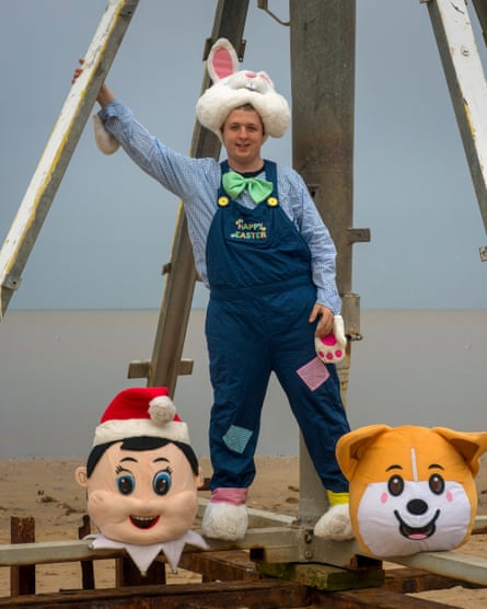 A young man dressed in dungarees and a bunny head and paws.