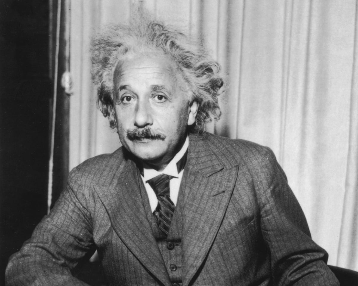 Black and white photo of Albert Einstein sitting at a table