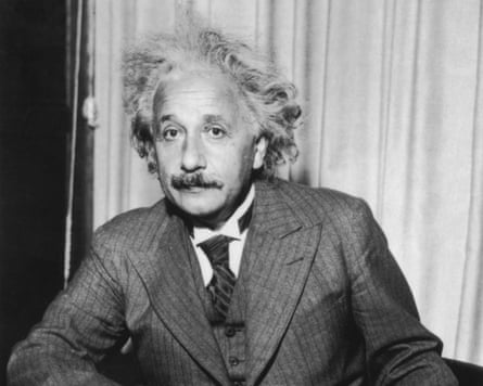 Black and white photo of Albert Einstein sitting at a table