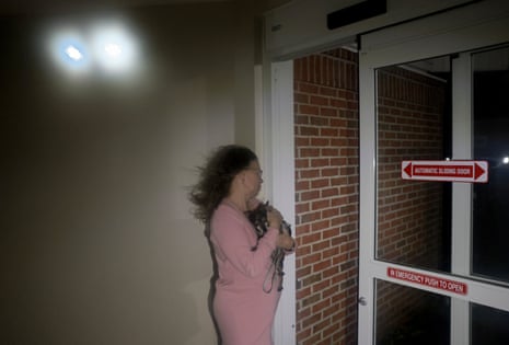 A woman holding her dog looks out the door of a hotel.