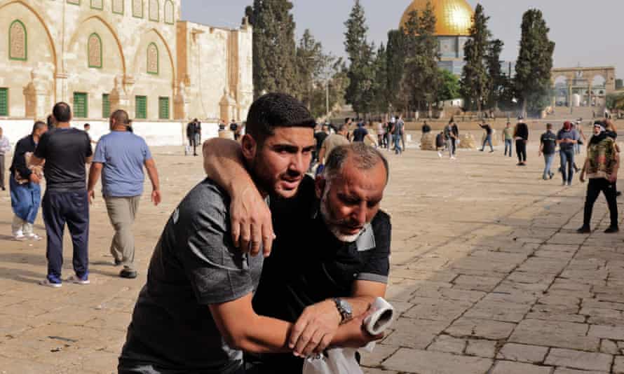 A Palestinian man helps a wounded fellow protester during clashes with Israeli security forces at Jerusalem’s al-Aqsa mosque.