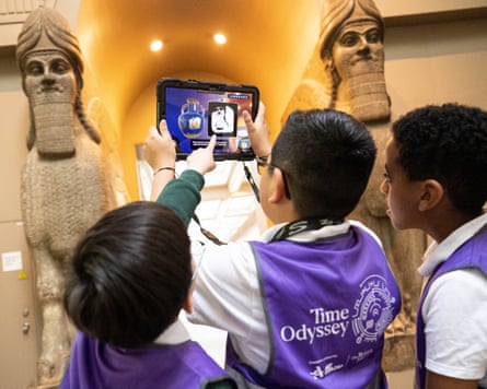Children holding up an iPad in front of two colossal statues of winged human-headed lions at the British Museum