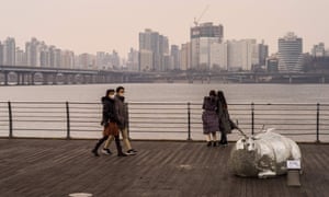 People walk on a deck along the Han River in Seoul on 29 December as South Korea announces it will extend stricter social distancing rules for two weeks.