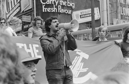 man speaks into megaphone, with a wrigley’s spearmint gum ad behind him, in a black and white photo
