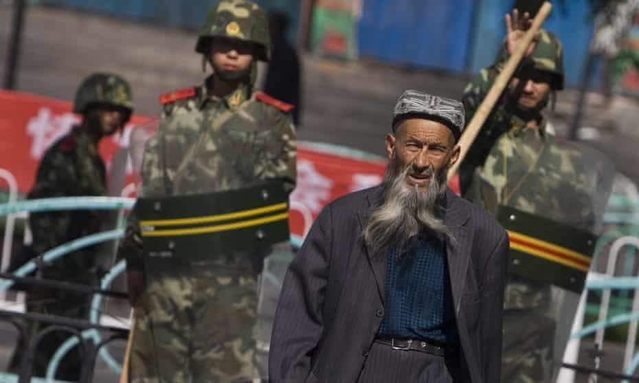 An ethnic Uighur man passes by security forces in Urumqi. The US has denounced China’s treatment of the Muslim minority. 