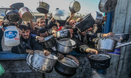 Palestinians hold out containers for food aid in Khan Younis.