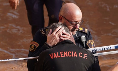 Members of the local police react to the news of one of their colleagues who died in the floods in Valencia, Spain, Thursday, Oct. 31, 2024. (AP Photo/Alberto Saiz)
