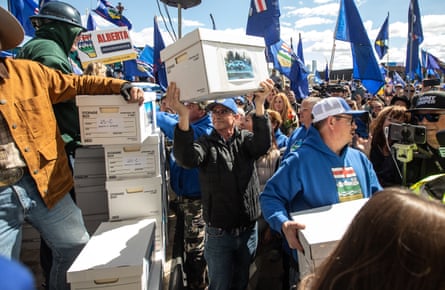 people carry cardboard boxes while others carry flags