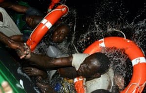 African migrants try to climb aboard a Spanish civil guard vessel after their makeshift boat capsized during a rescue operation at sea off the coast of Fuerteventura 12 November, 2004