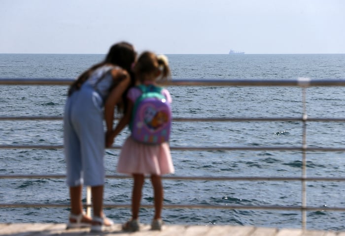 Children watch the Razoni cargo ship depart from Odesa port.