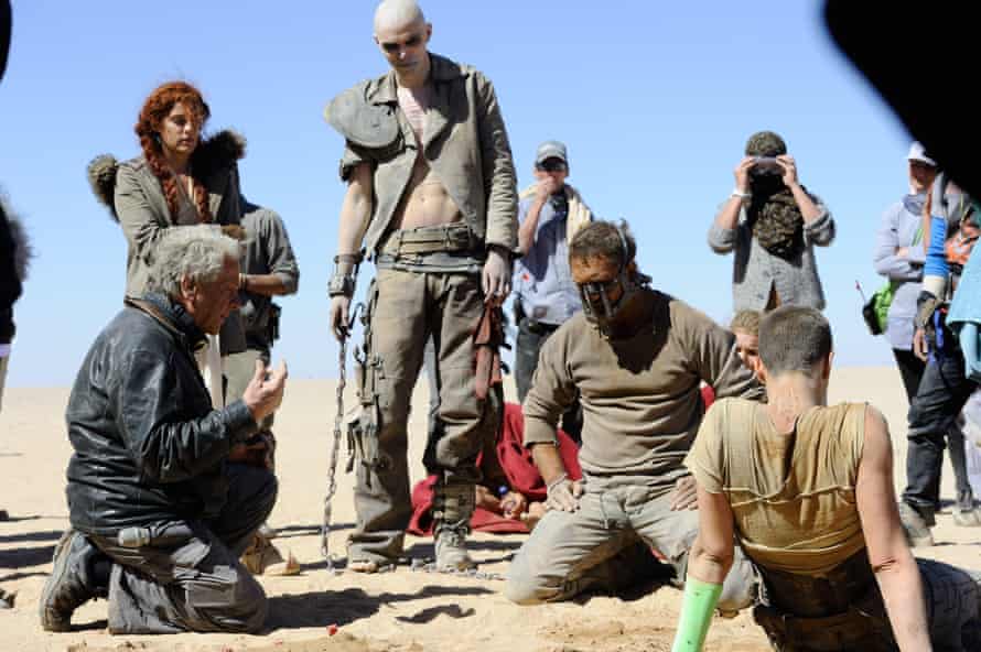 George Miller on the set of Mad Max: Fury Road with crew and cast members including Nicholas Hoult and Tom Hardy.
