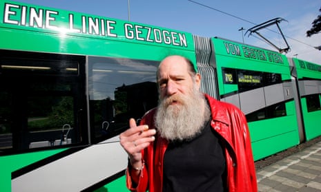 Lawrence Weiner in front of a tram inscribed with the sentence 'A line drawn from the first star of dusk to the last star of dawn' in German as well as English, in Düsseldorf, 2008.