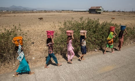 Girls carry buckets of clean water through drought-affected land near Makassar, Sulawesi, Indonesia