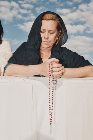 A woman holding rosary beads with her eyes closed