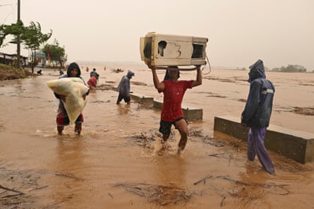 People carry their belongings as the river swells after heavy rains from Typhoon Toraji in Ilagan City, Isabela province