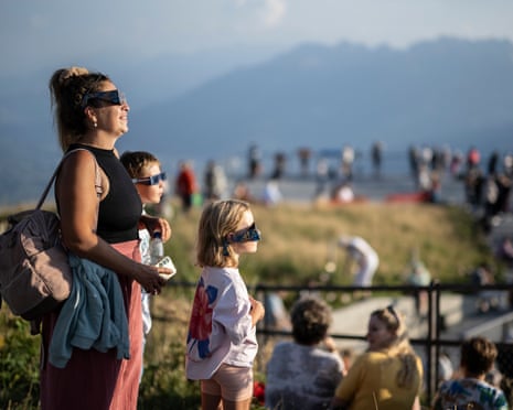 Spectators watch the beginning of a partial solar eclipse on the mountain Hoher Kasten in Bruelisau, Switzerland.
