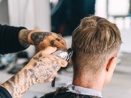 Rear view of a young man in a barbershop, having his hair trimmed