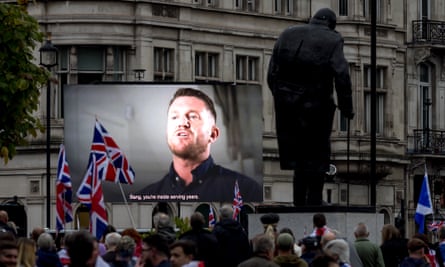 Supporters watch a video of Tommy Robinson on a large screen at a far-right march
