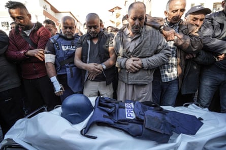 Al Jazeera’s Gaza bureau chief Wael Al-Dahdouh stands near the shrouded body of journalist Samer Abu Daqqa, who was killed by an Israeli strike in Gaza on 15 December 2023.