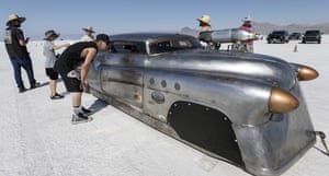 Wendover, US, US. People including a child wearing hats or caps inspect a vintage brushed-metal speedster
