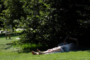 London, UK A person lies in the shade on Primrose Hill, London