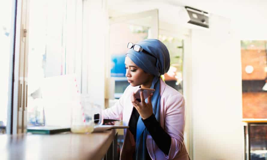 Young Muslim Woman Working in CafeUsing laptop and looking at papers in coffee shop