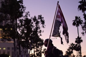 A man faces a row of police holding a burnt upsidedown US flag as protesters gather in downtown Los Angeles on May 27, 2020 to demonstrate after George Floyd, an unarmed black man, died while being arrested by a police officer in Minneapolis who pinned him to the ground with his knee.