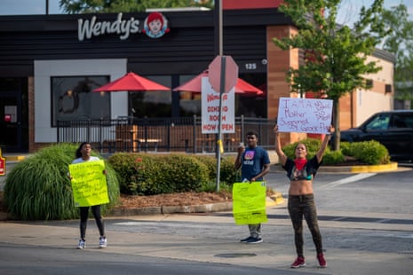 Protesters stand outside the Wendy’s where Rayshard Brooks was killed on Friday