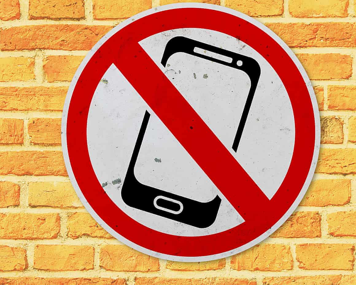 A no smartphones sign on a brick wall