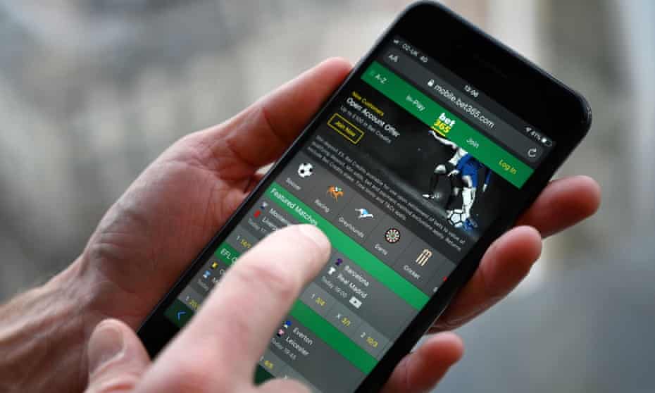 A man poses for a photograph with an online gambling website on a smartphone