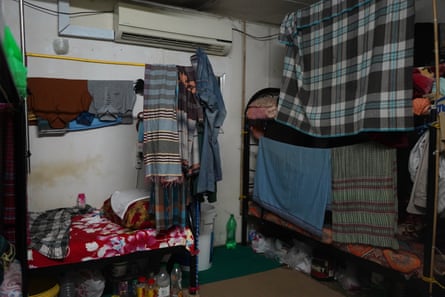 A room cluttered with personal possessions. Cloths hanging from string offer the only privacy for the bunk beds