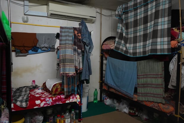 A room cluttered with personal possessions. Cloths hanging from string offer the only privacy for the bunk beds