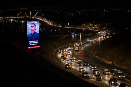 cars driving past screen showing news of bolsonaro arrest