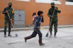 Soldiers clean ash from a street in the village of Santiago Xalitzintla