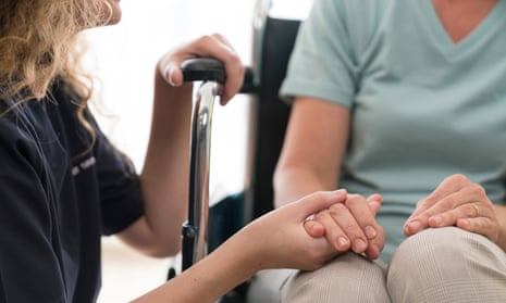 nurse holding hands of senior in wheelchair