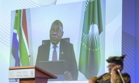President of South Africa Cyril Ramaphosa is seen on a screen as he delivers his speech past Nigeria’s Ngozi Okonjo-Iweala (R), director general of the World Trade Organization (WTO).