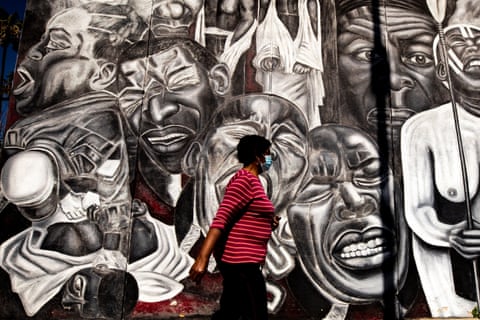 A woman walks by the 1992 mural Freedom Won’t Wait by Noni Olabisi in Los Angeles, created after the beating of Rodney King.