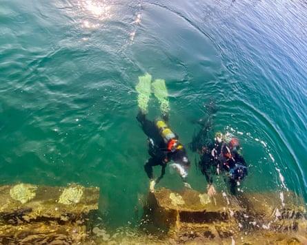 Two divers underwater can be seen at a breakwater from above