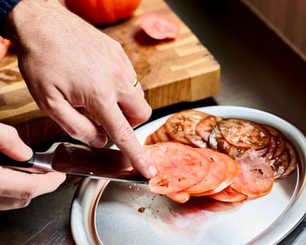 Sliced tomatoes being put from the knife on to a steel plate