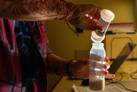 A person fills a baby bottle with formula