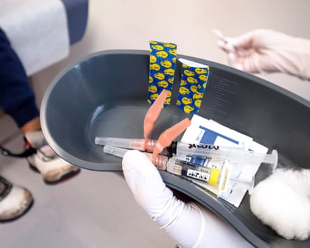 A rubber-gloved hand holds a dish of vaccines