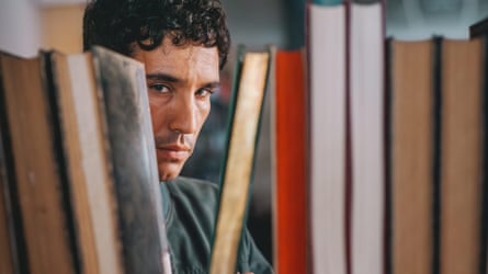 A man looking through a gap in a row of books
