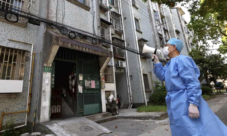 A volunteer uses a megaphone to talk to residents at an apartment building in Shanghai.