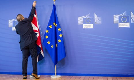 An officials takes down the Union flag next to the EU flag