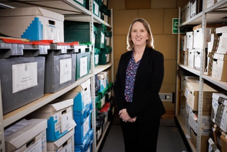 Jo Smith in a dark basement surrounded by shelves full of cardboard boxes of files