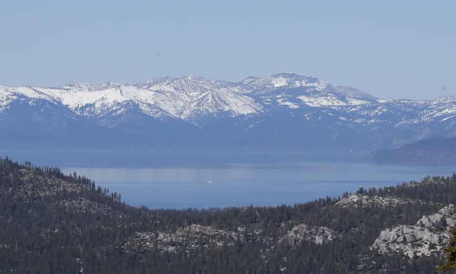 A picturesque landscape shows Lake Tahoe with its snow-capped mountains in the distance.